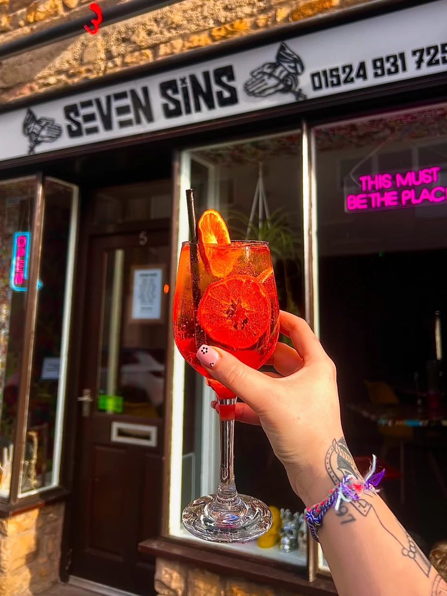 A bright red cocktail held outside the Seven Sins entrance
