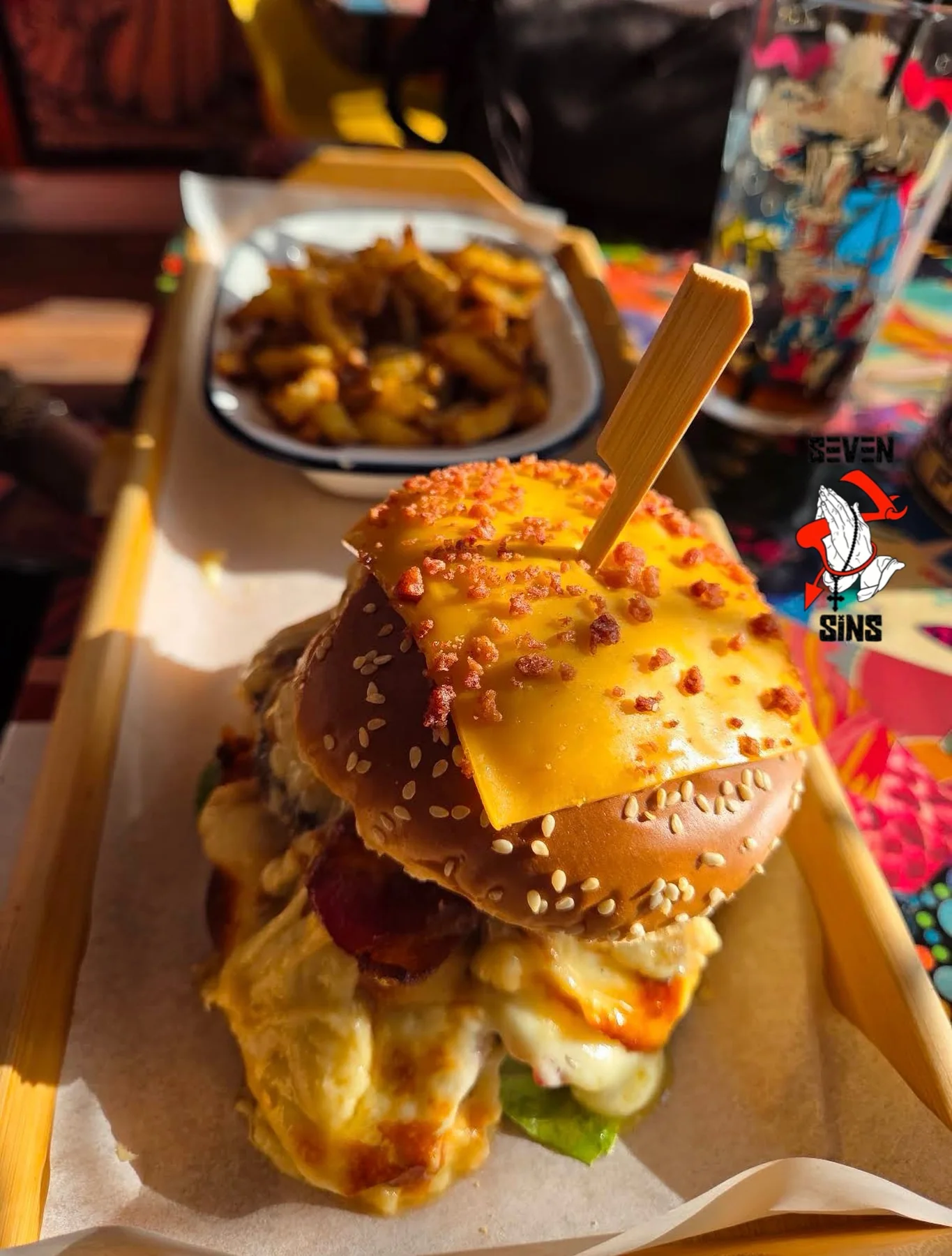 A tall burger served with seasoned fries